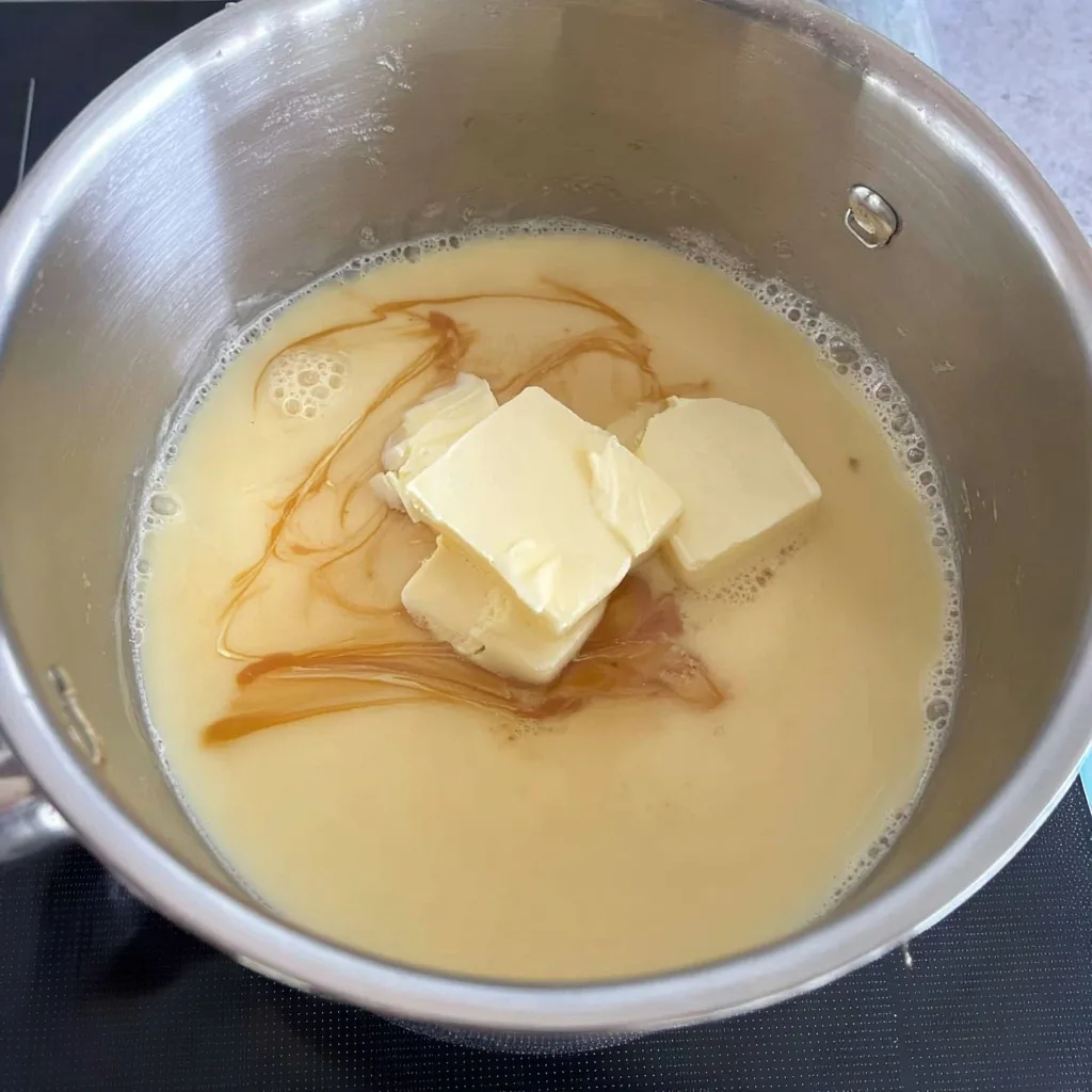 Sweetened condensed milk and butter melting together in a saucepan for caramel slice filling