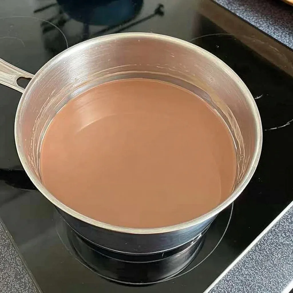 Melted milk chocolate in a saucepan on the stove, ready to top a caramel slice
