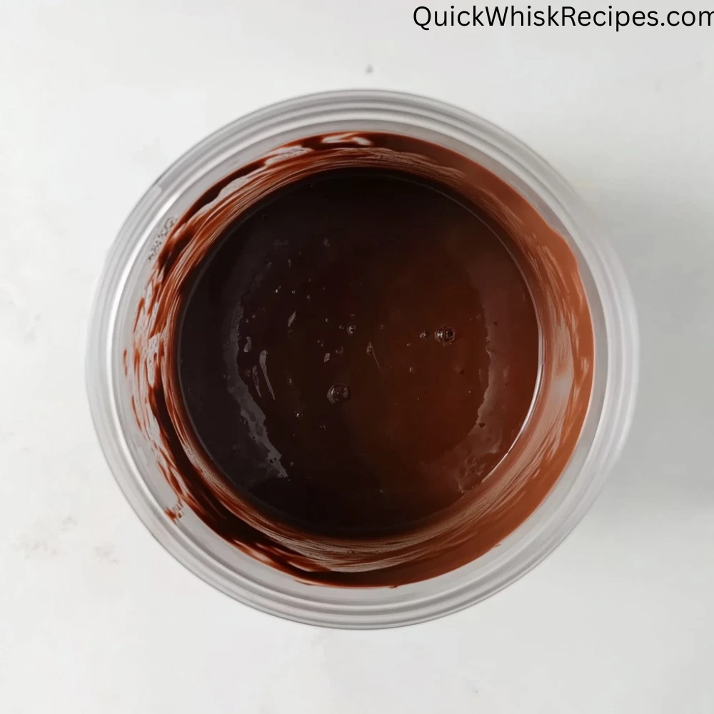 Overhead shot of thick, glossy chocolate tofu pudding inside a transparent blender cup with streaks of pudding along the rim.