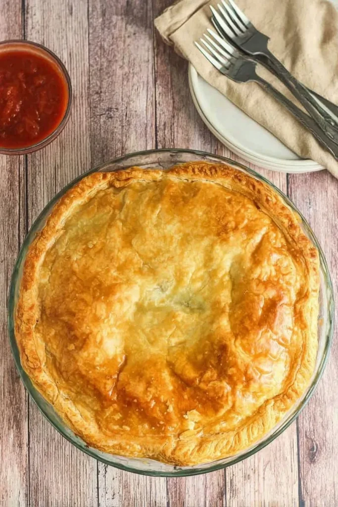 Freshly baked golden mince and cheese pie in a glass dish with puff pastry top