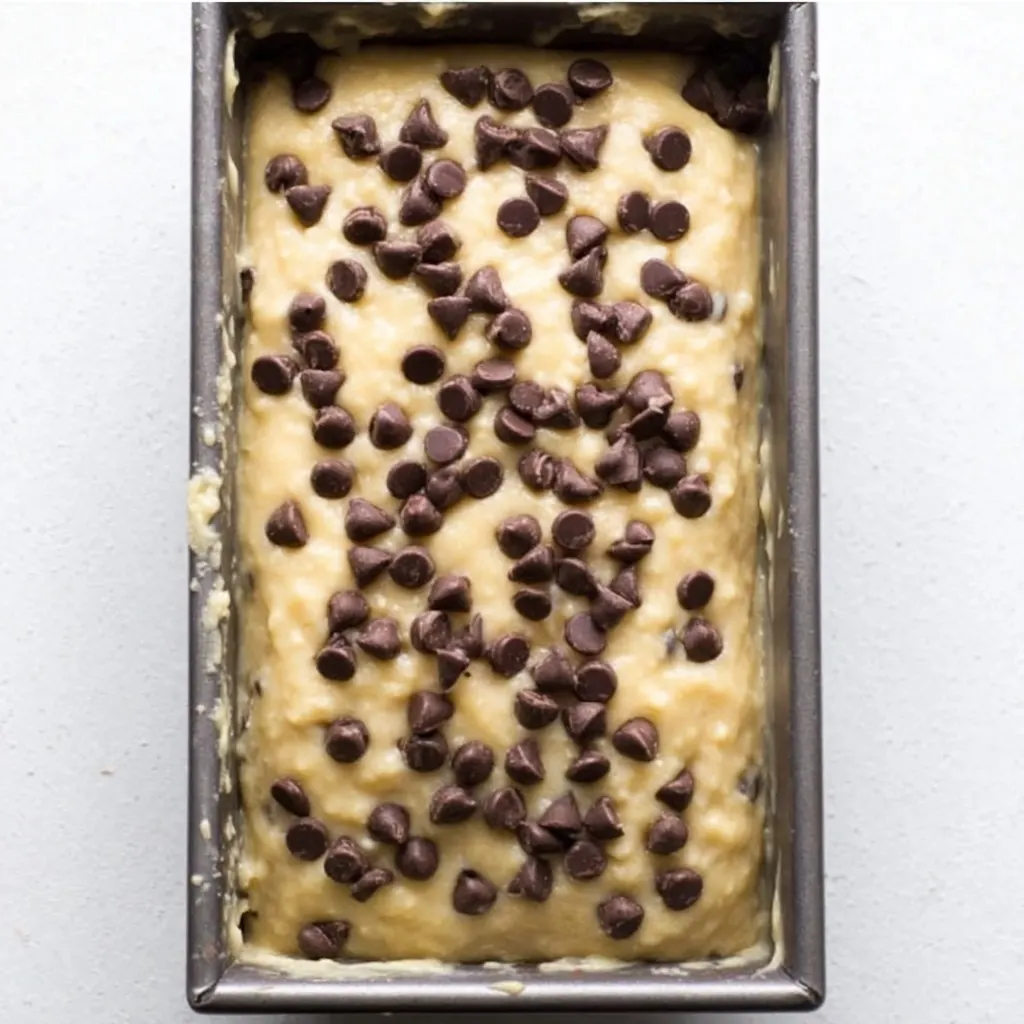 banana bread batter topped with chocolate chips in a loaf pan before baking