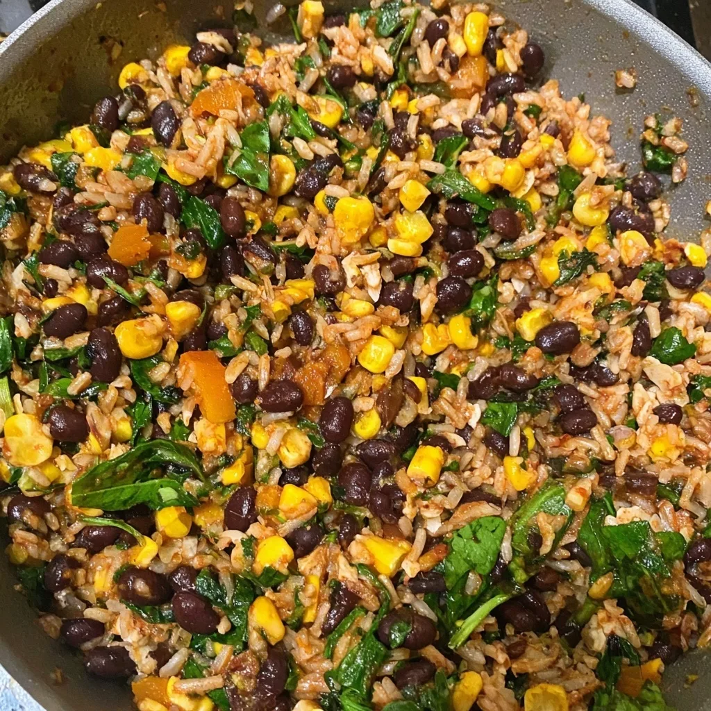 Vegan stuffing mixture of rice, black beans, corn, and spinach cooking in a skillet for stuffed butternut squash