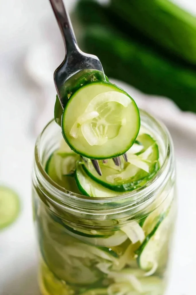 Close-up of cucumber and onion refrigerator pickles lifted from a jar with a fork
