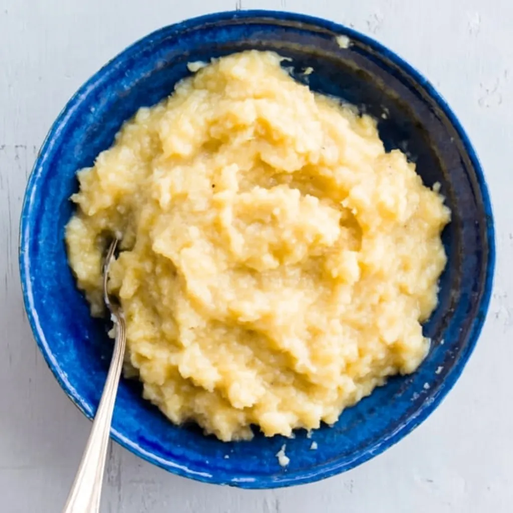 mashed ripe bananas in a blue bowl with spoon, ready for chocolate chip banana bread batter