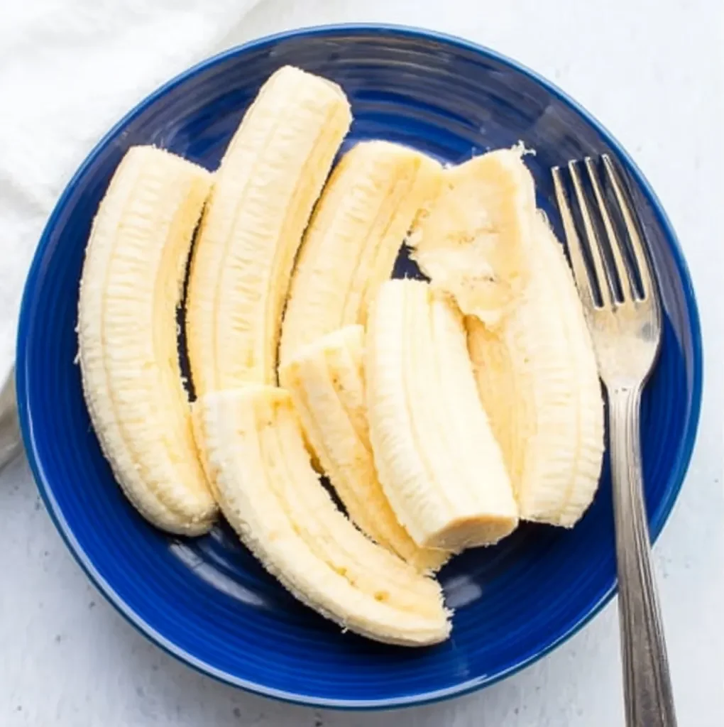 peeled ripe bananas in a blue bowl with a fork, ready to mash for banana bread