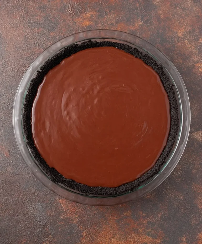 Pie dish with Oreo crust filled with chocolate pudding mixture for Chocolate Cream Pie.
