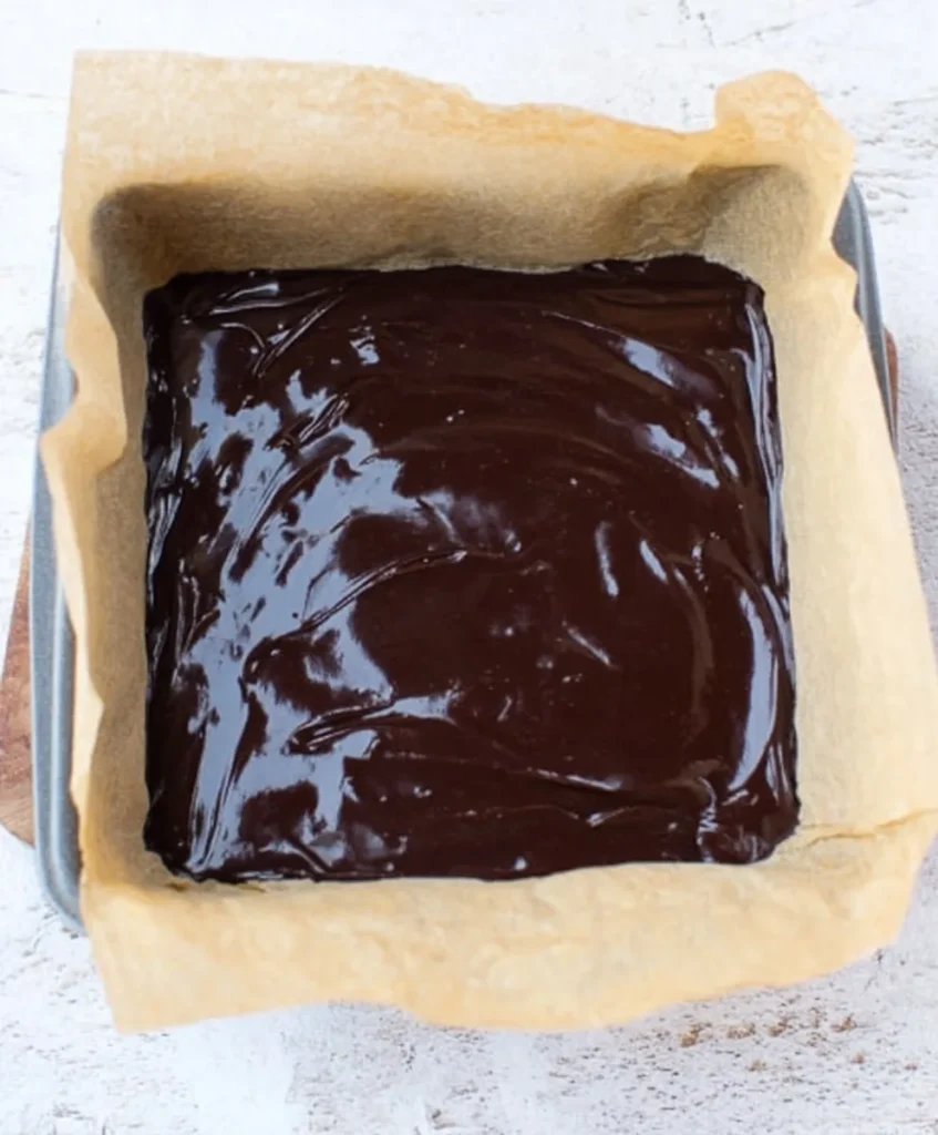 Chocolate sugar free fudge mixture poured into a parchment lined pan before chilling