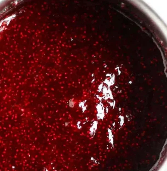 Thick, glossy raspberry chia seed jam in a saucepan after cooking, showing its rich color and perfect texture.