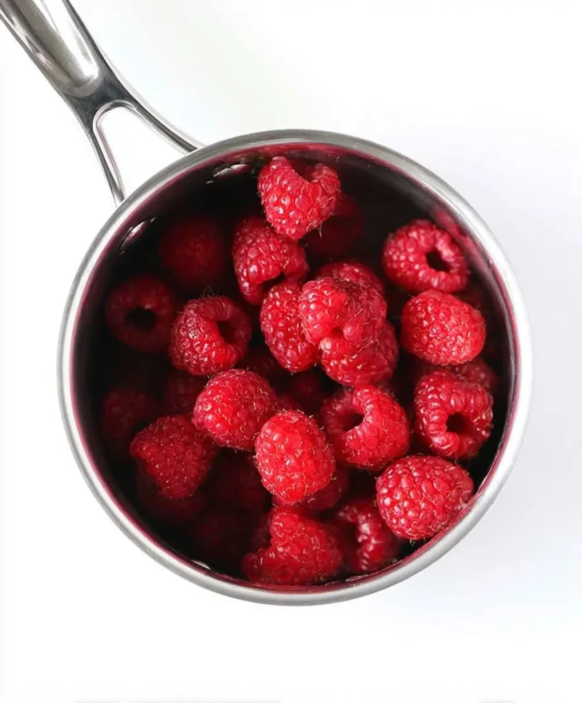Fresh red raspberries in a small stainless steel saucepan, ready to be cooked for homemade chia seed jam.
