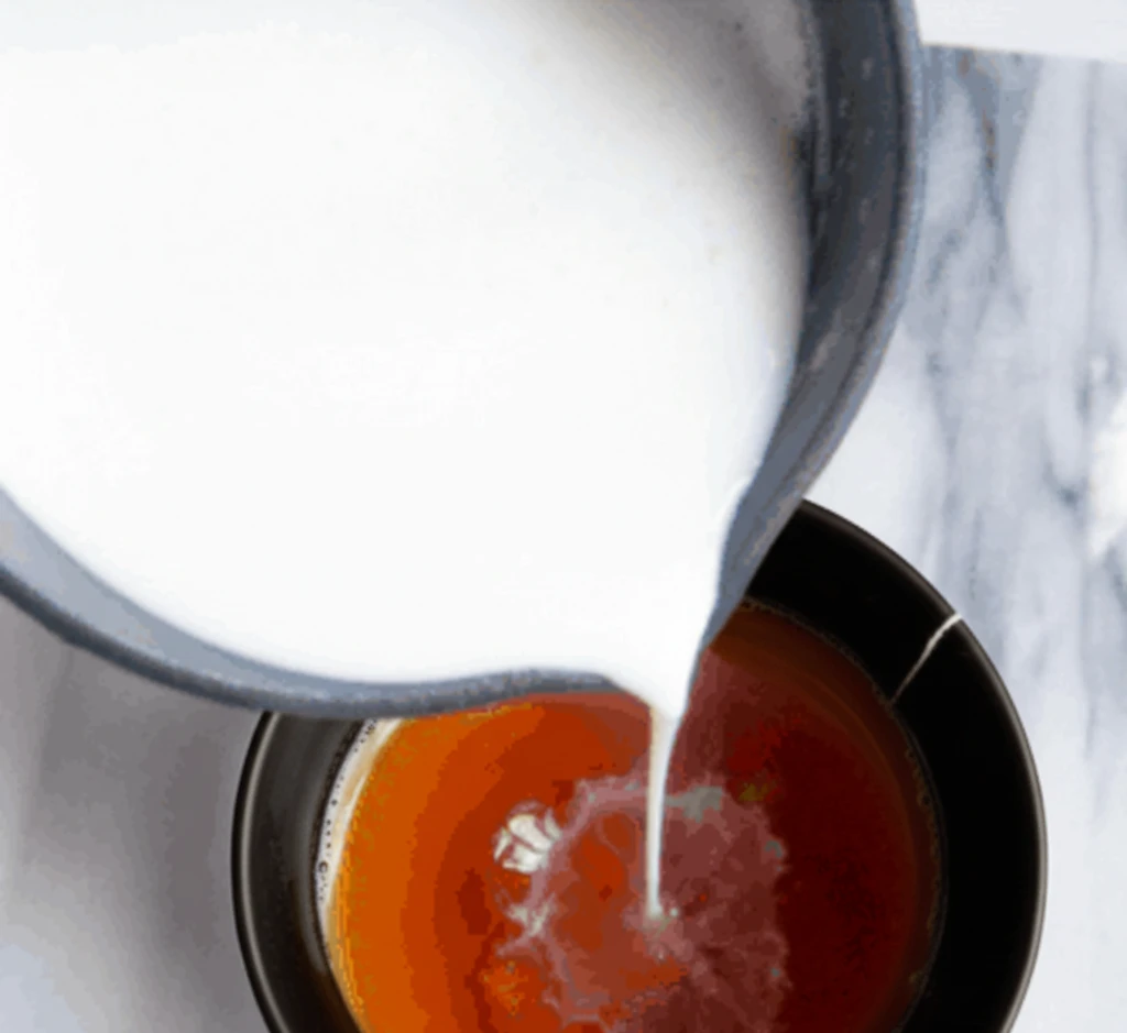 Pouring steamed milk into brewed Earl Grey tea to make a London Fog Latte.