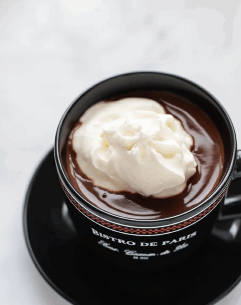 Rich Paris hot chocolate in a black “Bistro de Paris” cup topped with whipped cream — indulgent and smooth.