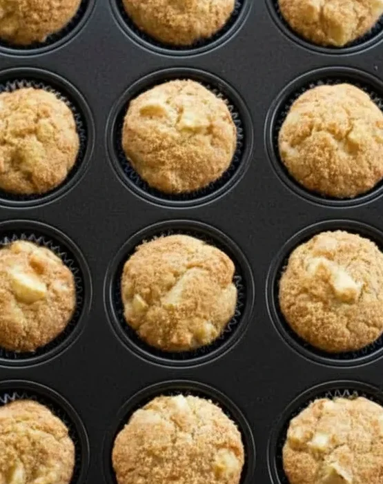 Muffin tray filled with freshly baked apple muffins straight from the oven.