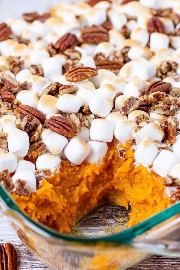 Baked sweet potato casserole in a glass dish with toasted marshmallows and pecans, creamy orange filling and classic homemade texture