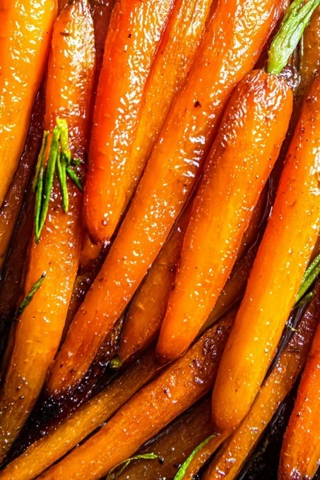 Whole brown sugar glazed carrots with a glossy caramelized glaze and green tops