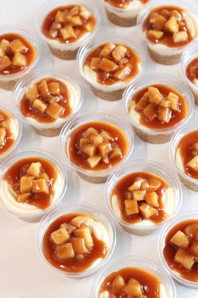 Caramel apple dessert cups topped with diced apples and caramel sauce in small clear plastic cups