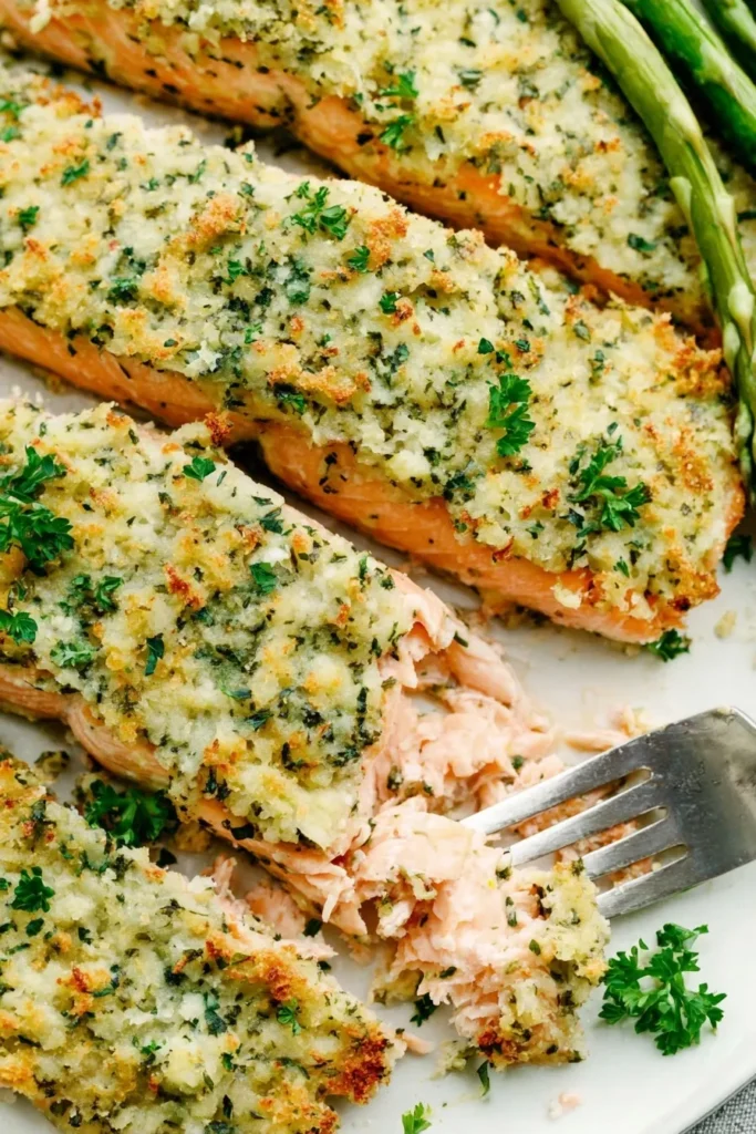 Flaky Parmesan crusted salmon breaking apart with a fork, showing tender baked salmon inside
