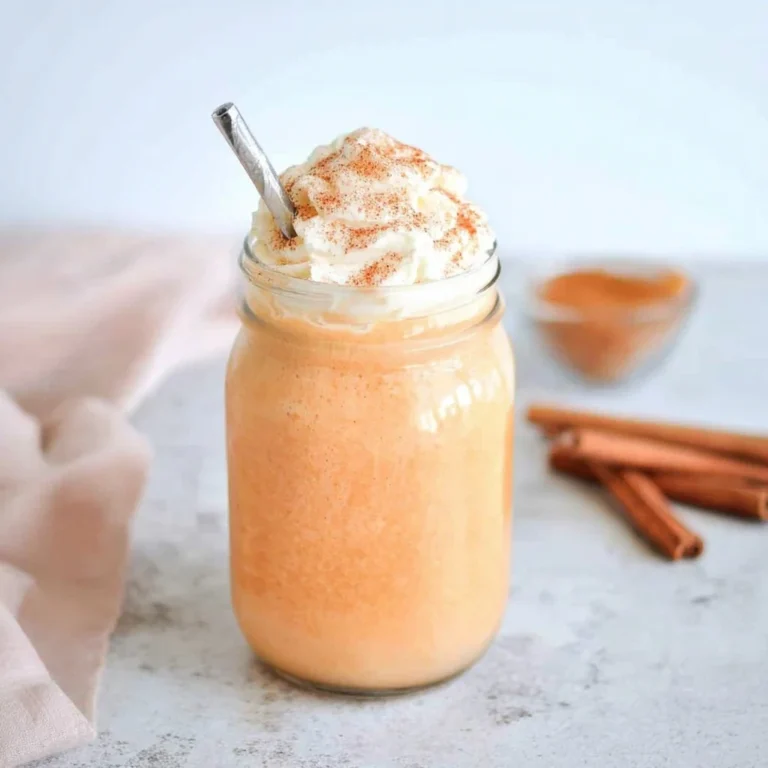 Creamy pumpkin spice milk in a mason jar topped with whipped cream and cinnamon, with cinnamon sticks in the background.