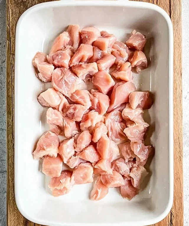 Raw chicken pieces arranged in a baking dish before seasoning