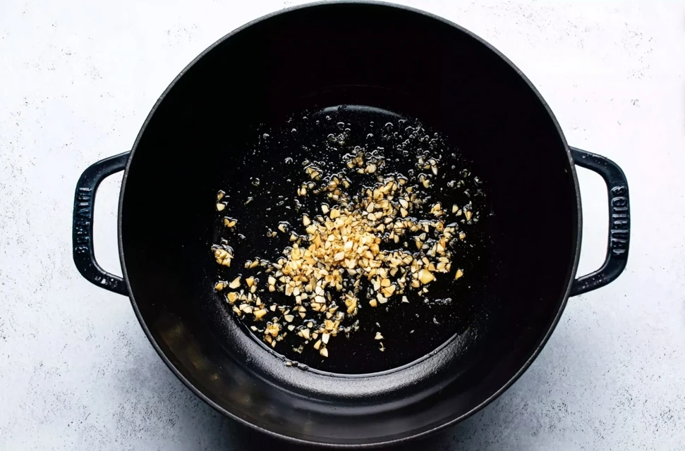 Minced garlic sautéing in oil in a pot as the base for dumpling soup
