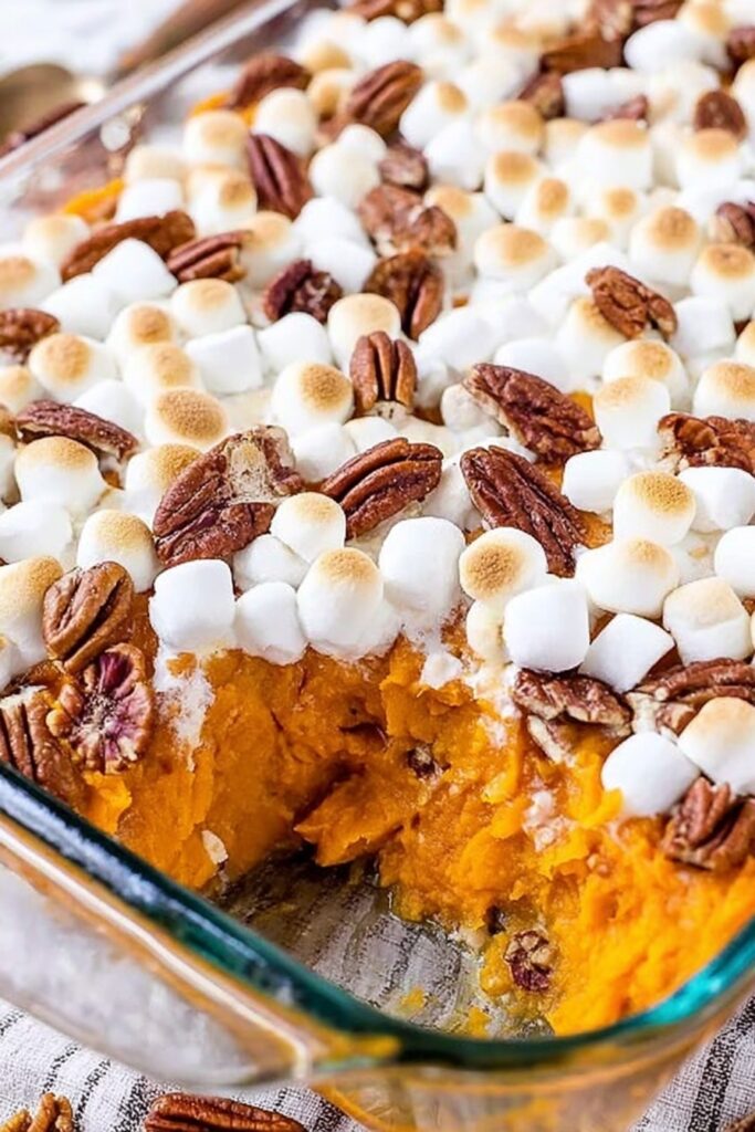 Sweet potato casserole baked in a glass dish with toasted marshmallows and pecans, creamy orange filling and classic homemade texture
