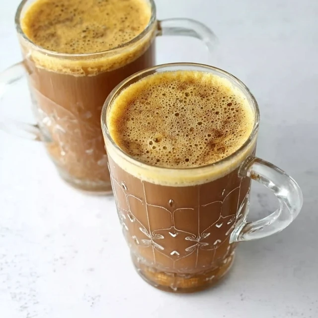 Hot banana milk coffee served in clear glass mugs with creamy foam on top