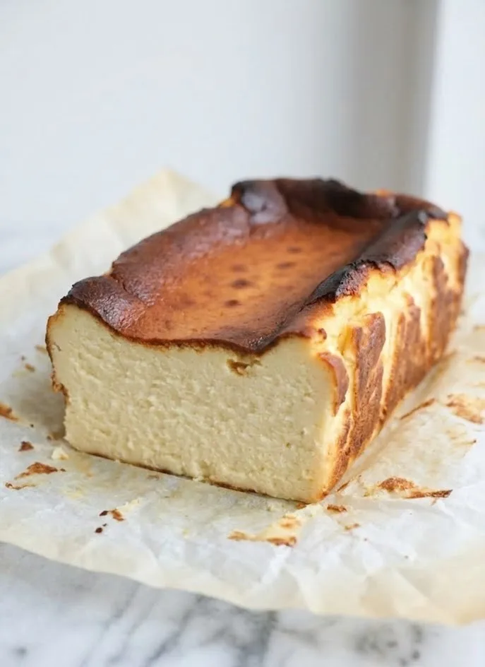 Slice of Basque cheesecake in a loaf pan showing a creamy center and caramelized top
