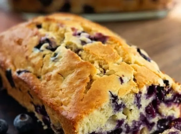 Golden blueberry cream cheese loaf with cracked top and juicy blueberry swirls