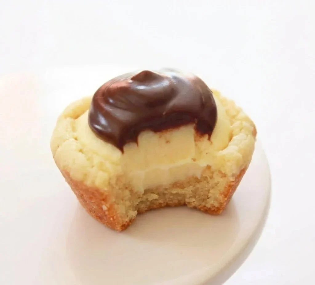 Boston cream pie cookies with vanilla cream filling and chocolate topping, bite taken