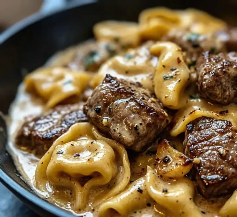 Close-up of cracked garlic steak tortellini coated in creamy Creamhouse sauce with seared steak pieces