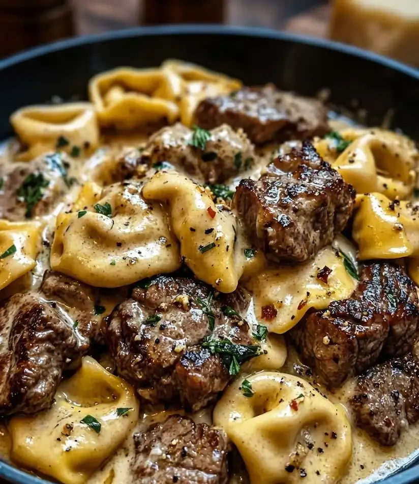 Cracked garlic steak tortellini in creamy Creamhouse sauce with seared steak bites, skillet close-up
