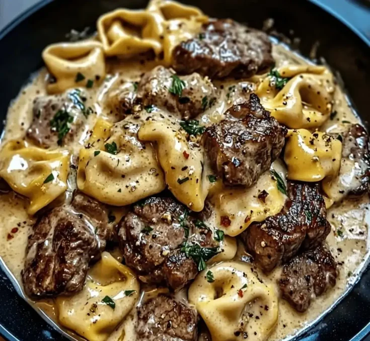 Close-up of cracked garlic steak tortellini coated in creamy Creamhouse sauce with seared steak pieces