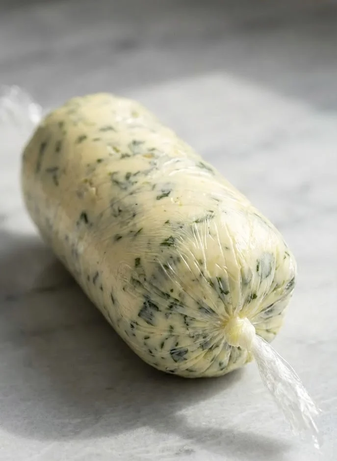 Homemade garlic butter log wrapped in parchment with fresh herbs