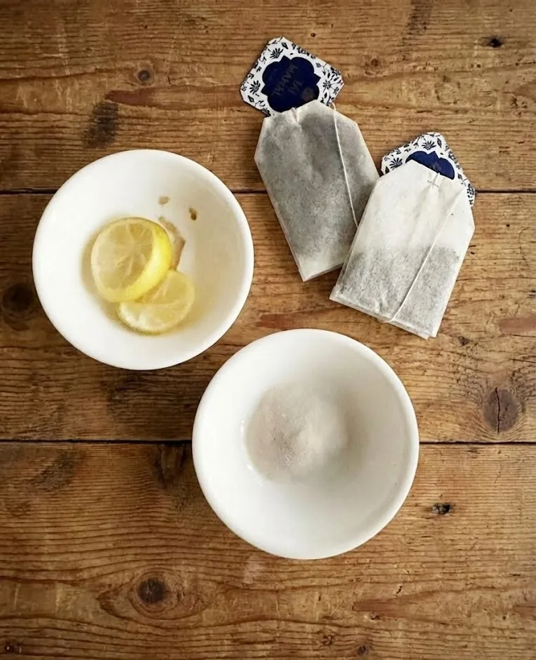 Ingredients for gelatin trick recipe including unflavored gelatin, lemon slices, and tea bags on a wooden surface
