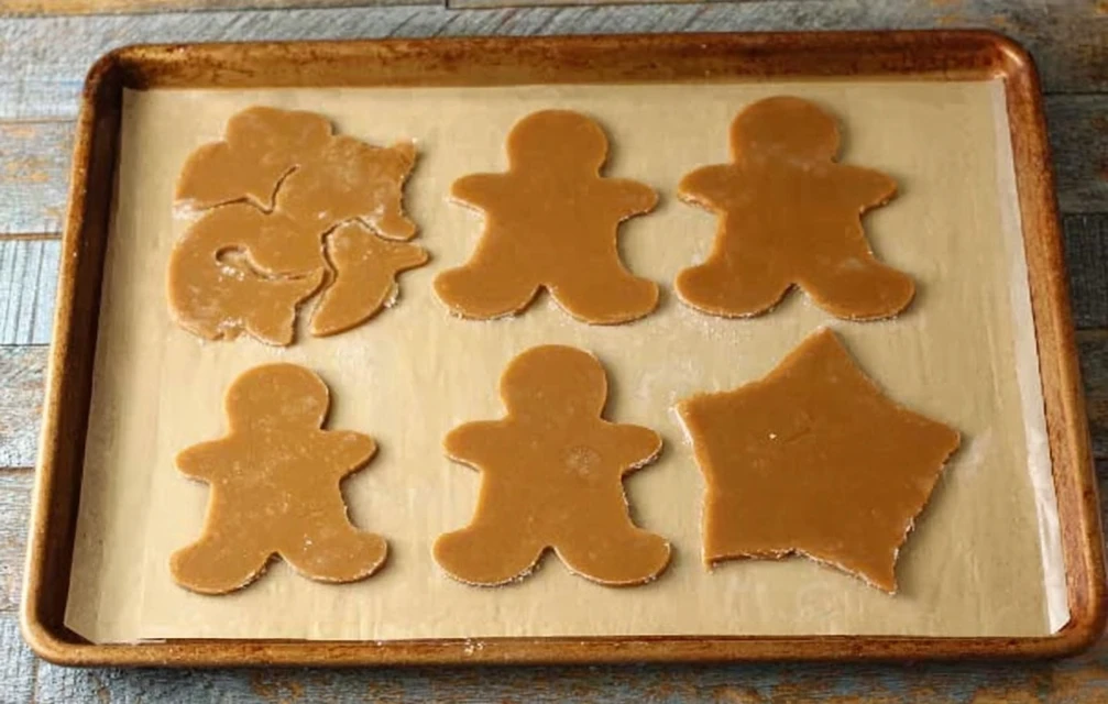 Cut-out gingerbread cookies shaped and ready to bake on a parchment-lined tray