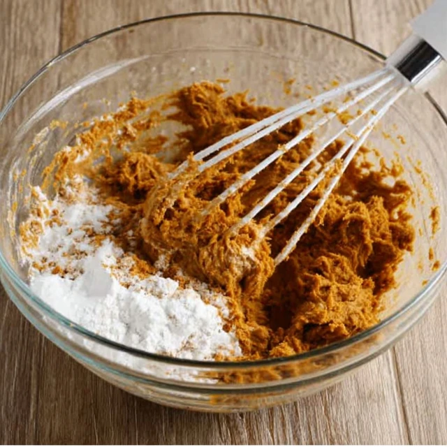 Mixing dry and wet ingredients together to form gingerbread cookies dough in a bowl