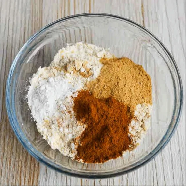 Bowl of dry ingredients for gingerbread cookies including flour, ginger, cinnamon, and spices