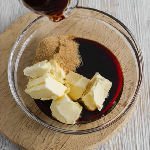 Wet ingredients for gingerbread cookies with butter, brown sugar, and molasses in a mixing bowl
