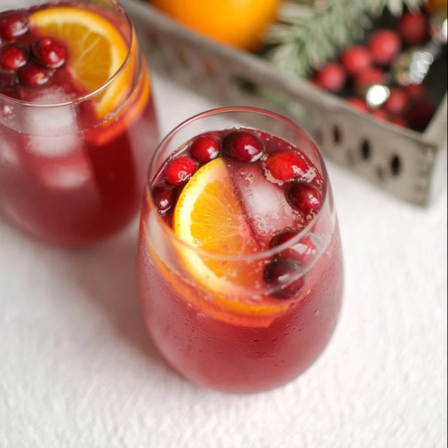Glass of non-alcoholic holiday punch with cranberry juice, orange slice, fresh cranberries, and ice