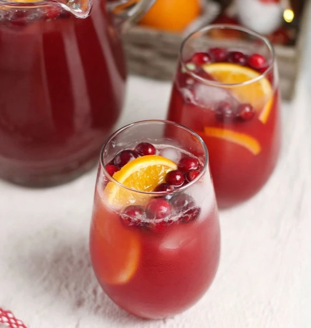 Non-alcoholic holiday punch made with cranberry juice, orange slices, and fresh cranberries served over ice