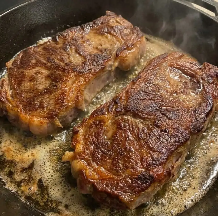 Seared steak cooking in a skillet with golden brown crust, ready for creamy steak pasta recipe
