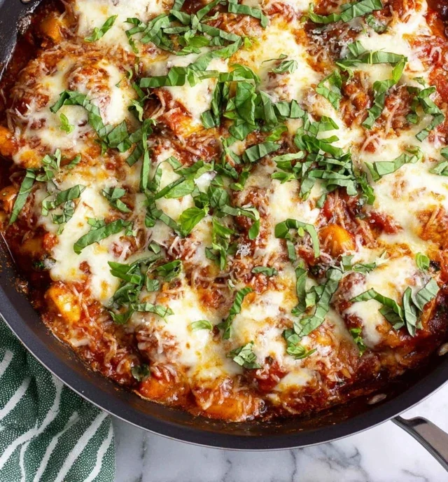 Skillet chicken parmesan gnocchi topped with melted mozzarella, marinara sauce, and fresh basil