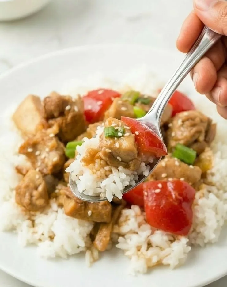 Spoonful of sweet Hawaiian crock pot chicken with rice, pineapple, bell peppers, green onions, and sesame seeds