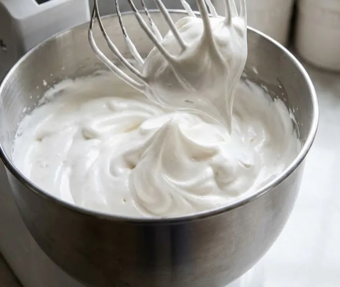 Whipping marshmallow mixture in stand mixer until thick glossy peaks form