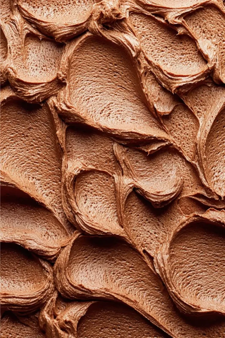 Close-up macro view of the silky, pipeable texture of chocolate peanut butter buttercream frosting.