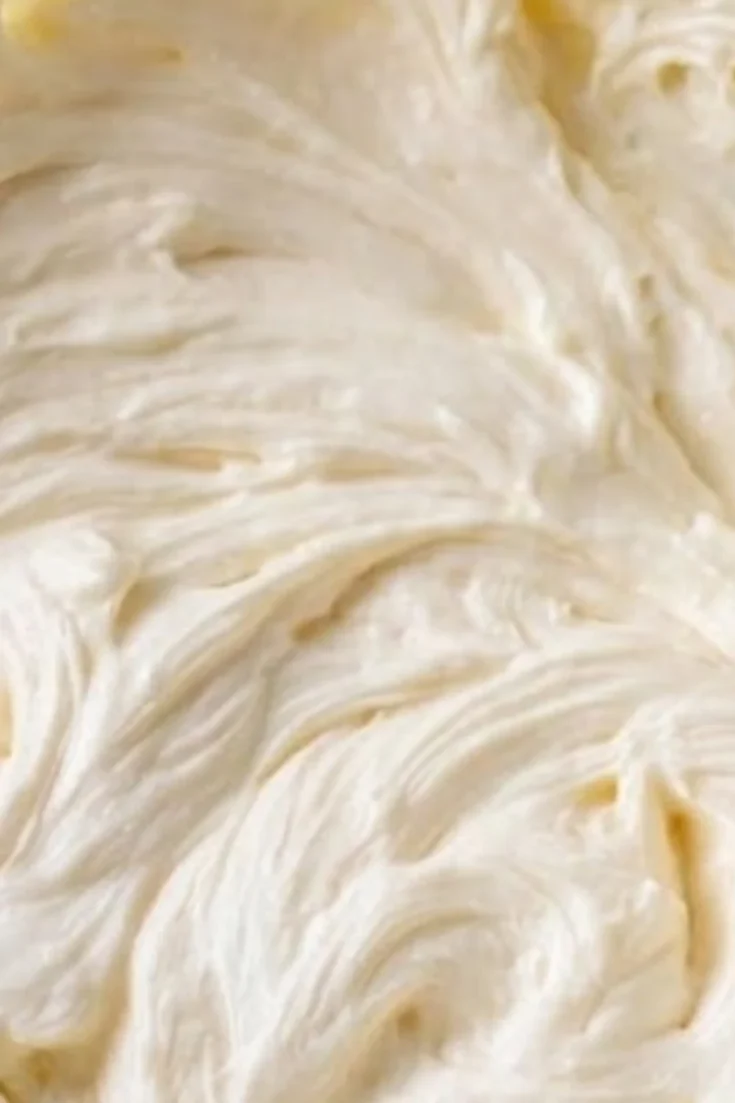 Extreme close-up of the ripples and swirls in a batch of thick, stable cream cheese frosting.