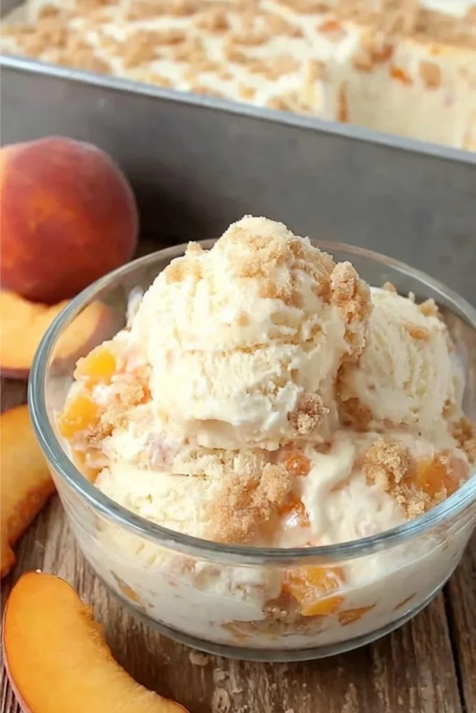 A close-up shot of Peach Pie Ice Cream in a glass bowl showing textures of fruit swirls and crunchy pie crust bits.