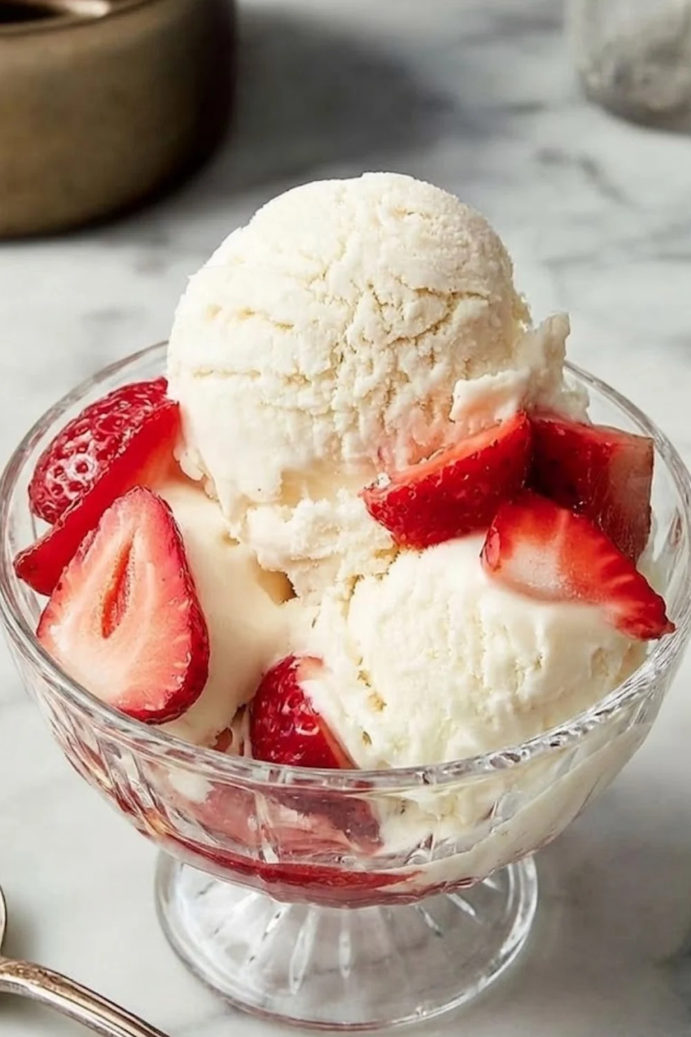 Gourmet vanilla ice cream served in a crystal glass bowl with fresh red strawberries.