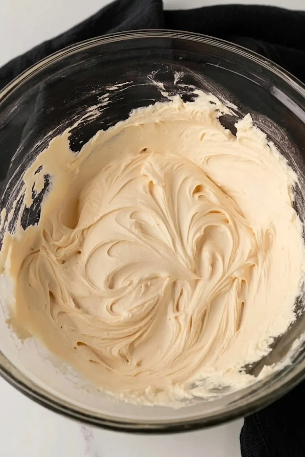 Freshly whipped salted caramel frosting in a glass mixing bowl, showcasing its airy and pipeable consistency.