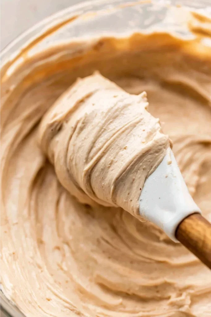 Side view of a spatula with a thick swirl of Chai Spice Buttercream frosting, ready to be piped onto a cake.