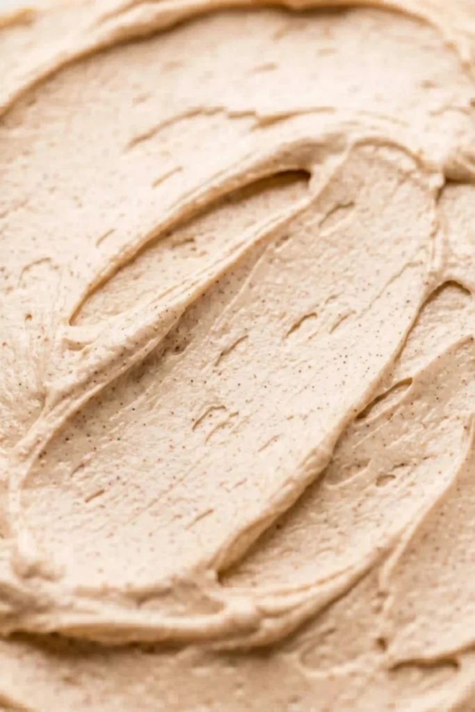 Extreme close-up showing the smooth, silky texture and spice flecks of homemade Chai Spice Buttercream spread thin.